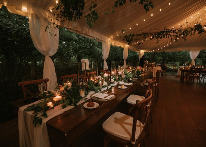 a dining table set up under a wedding tent